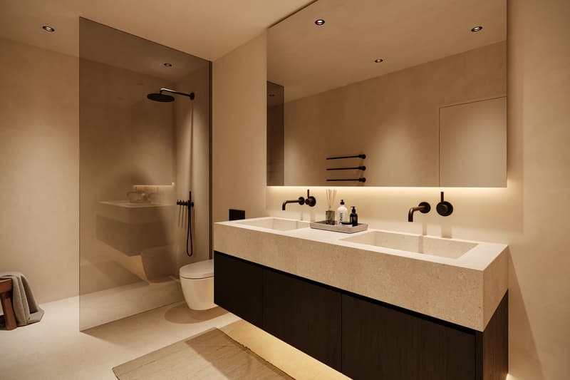 Spacious bathroom with a large vanity countertop, double sinks, black fixtures, and a walk-in shower with a rainfall showerhead. The room has a minimalist and modern design with warm lighting and neutral color tones.
