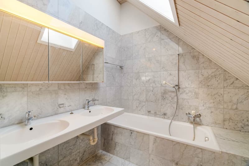 Bathroom with double sink, bathtub, and marble tiles