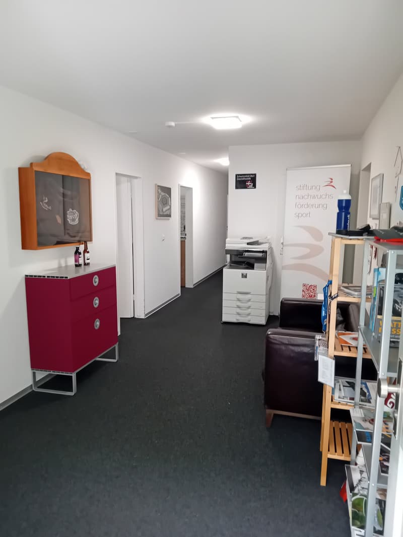 empty room, white walls, red cabinet, printer, couch, shelves, banner