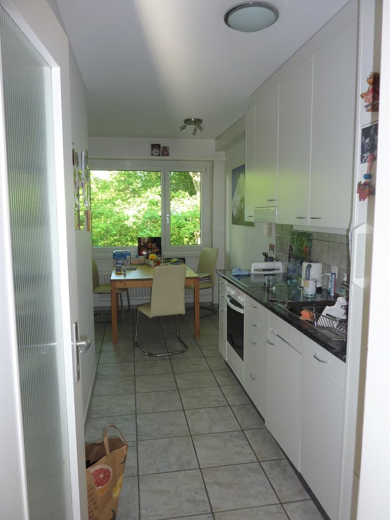 modern kitchen with white cabinets, tiled floor, dining table, chairs, large windows, view of trees