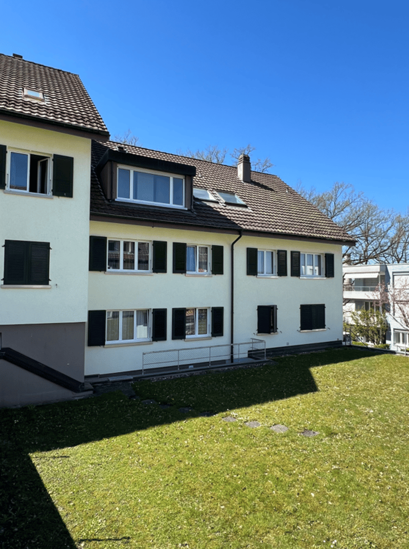 3 story house, white walls, brown roof, multiple windows, green lawn