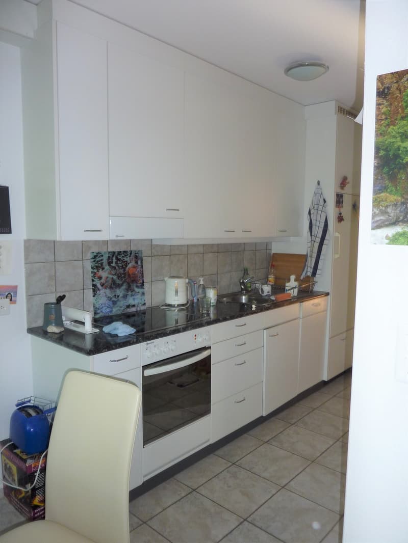 modern kitchen with white cabinets, black countertops, built-in oven, dishwasher, toaster, refrigerator, sink, faucet, and various kitchen utensils
