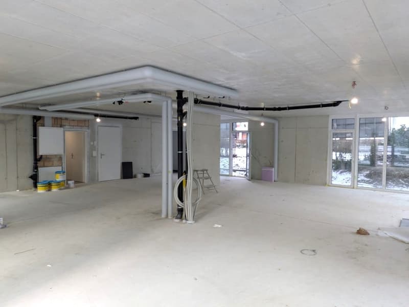 Empty room with unfinished walls and ceiling, pipes and lights installed, glass windows, wooden ladder, empty room, construction materials