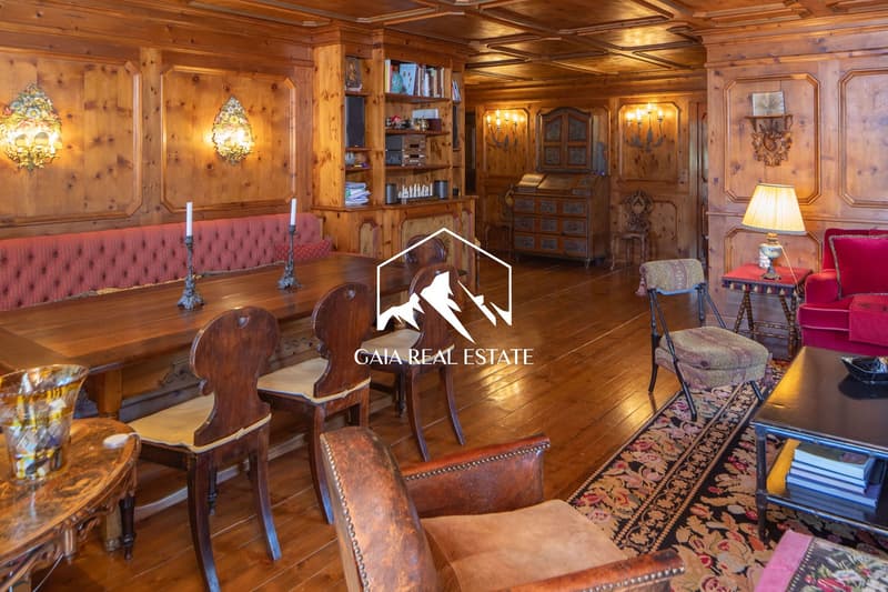 room with wooden walls, wooden floors, dining table, chairs, sofa, lamp, desk, books
