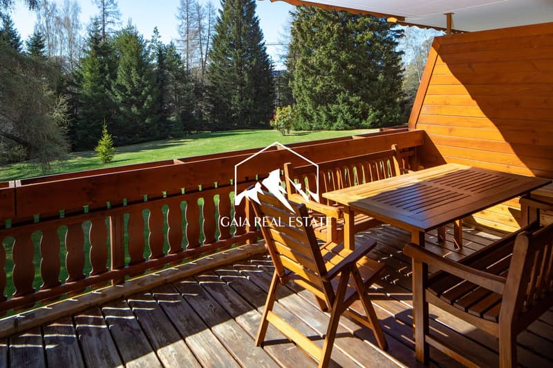 wooden balcony with a wooden fence, wooden table, wooden chairs, green grass view