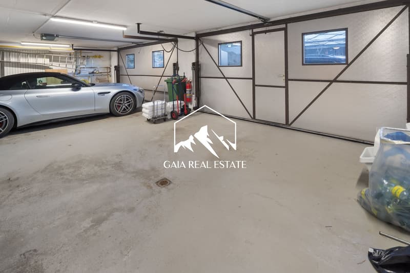 Empty garage with a silver car parked, a fire extinguisher, a trolley, and a storage box.