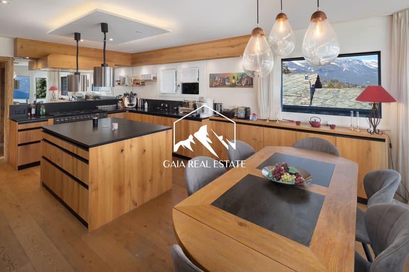modern kitchen with wooden cabinets, black countertops, large windows, dining table, view of mountains