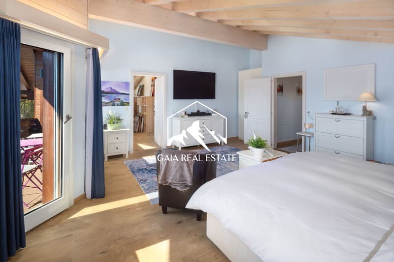 bedroom with double bed, wooden floor, blue curtains, glass door to balcony, white furniture, TV, rug, armchair, side table, lamp, picture frame
