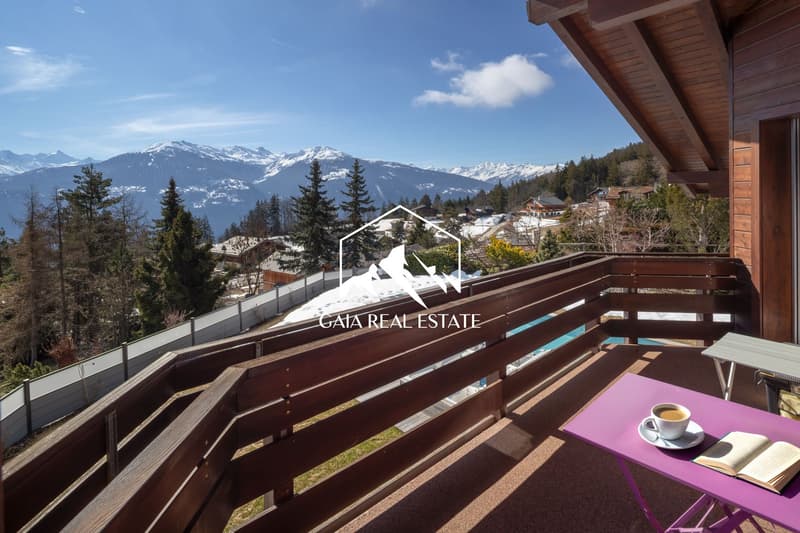 wooden railing, table with book and coffee, mountain view