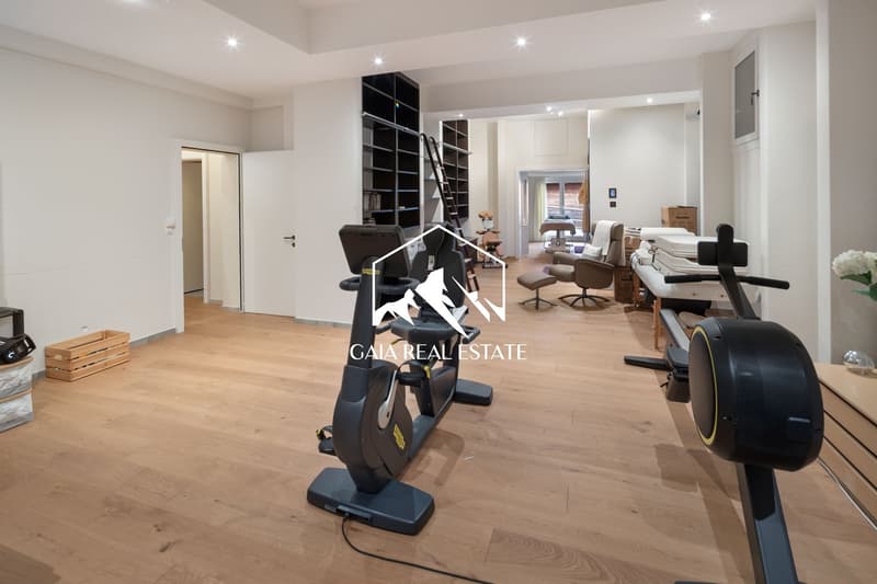 wooden floor, exercise equipment, white walls, open layout, storage boxes, ladder, furniture