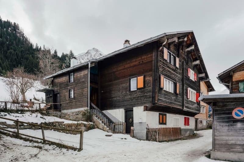 wooden exterior, multiple windows, steep sloped roof, snowy ground, surrounded by fences