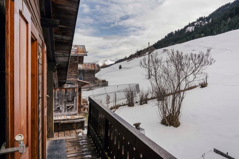 balcony of a chalet with view on snowy mountains