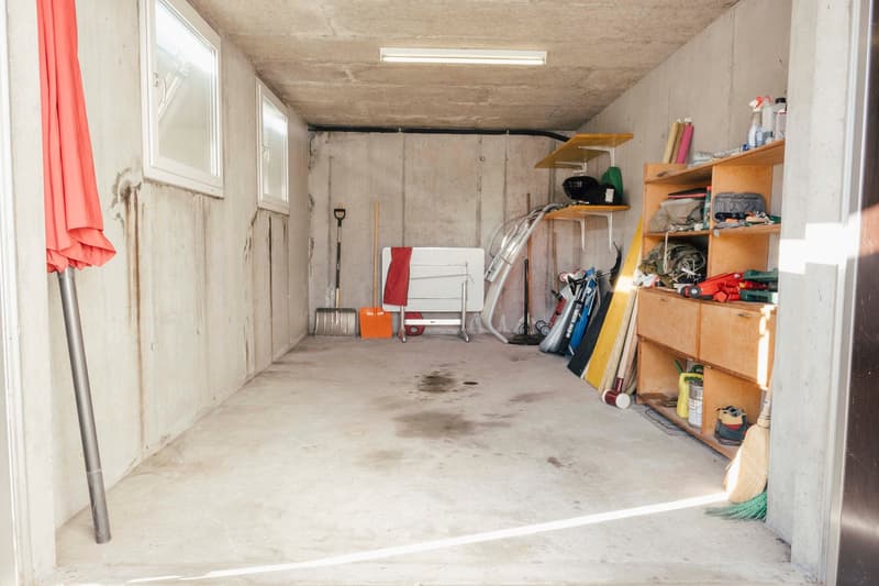 Storage room with concrete walls, shelves, and various tools and equipment