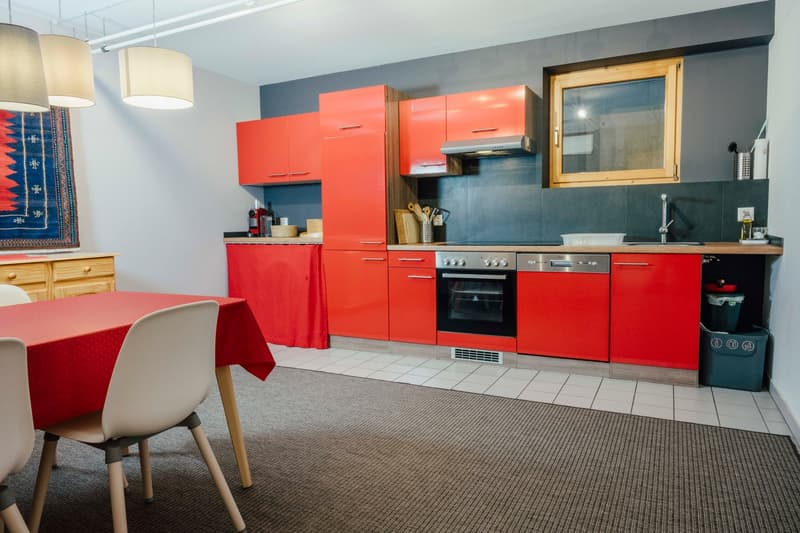 red cabinets, stainless steel appliances, white tiled floor, dining table, wooden chairs, carpet
