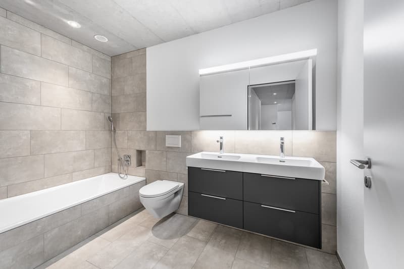 modern bathroom with white bathtub, two sinks, built-in cabinet with three drawers, modern toilet