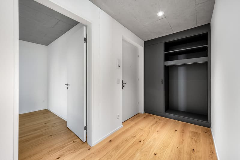 Empty room with white walls, hardwood floors, a wardrobe with an open door, and two closed doors