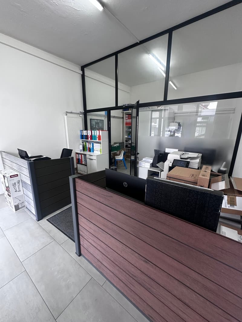 empty office with wooden desk, 2 chairs, printer, bookshelves, storage boxes