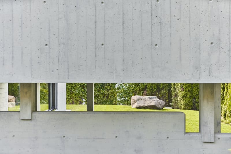 Concrete wall with holes, grassy area, large rock, trees, window