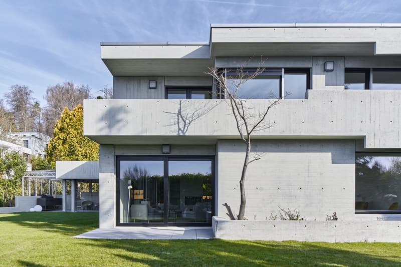 Modern concrete house, large windows, glass doors, balcony, outdoor seating area