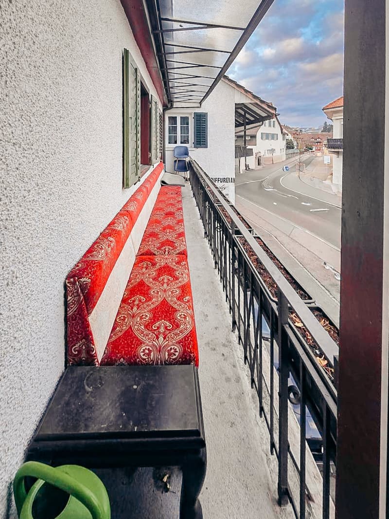 Balcony with a bench, black table, and a view of the street