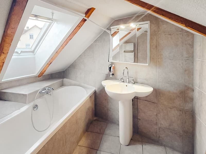 Bathroom with bathtub, sink, mirror, and wooden beams