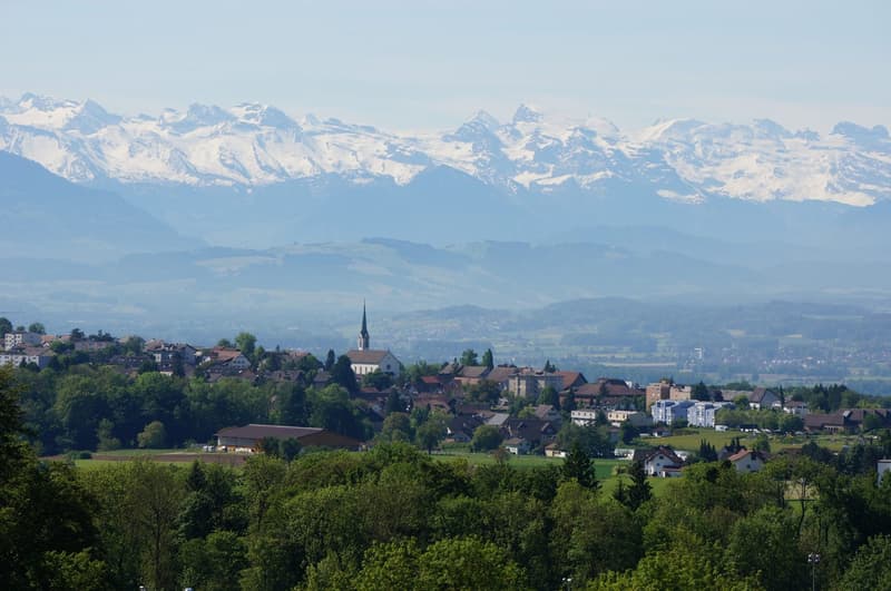 Panoramic view of a village with snow-capped mountains in the background