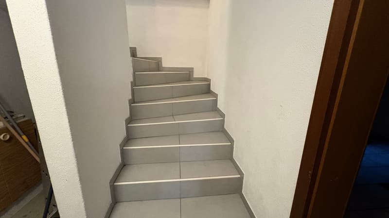 The image shows a set of concrete stairs leading up to a higher level. The stairs have a simple, minimalist design with clean lines and a neutral gray color.