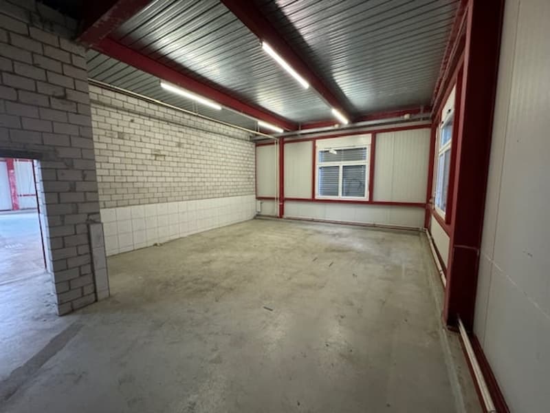 Empty room, metal roof, brick wall, ceiling lights, open doorway, two windows