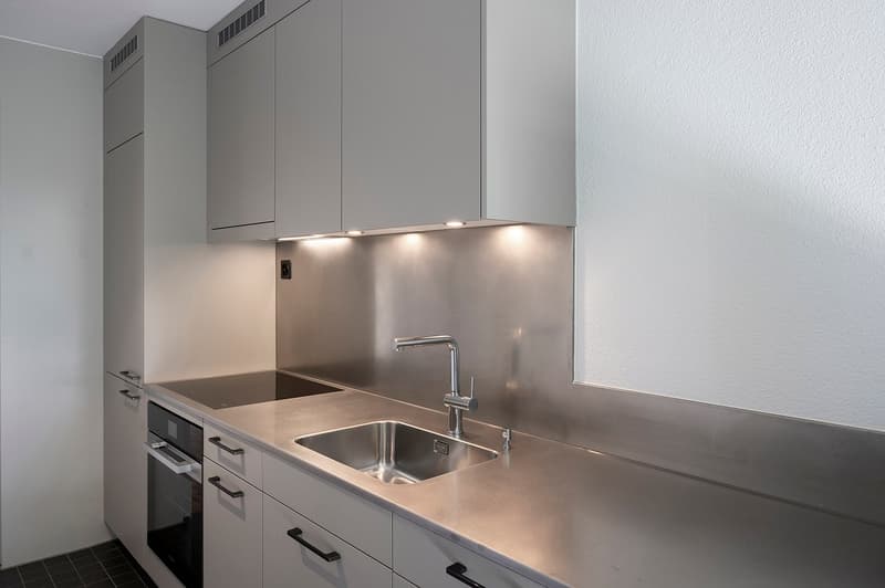 modern kitchen with stainless steel countertops, integrated dishwasher, washing machine, gas stove, and sink with faucet