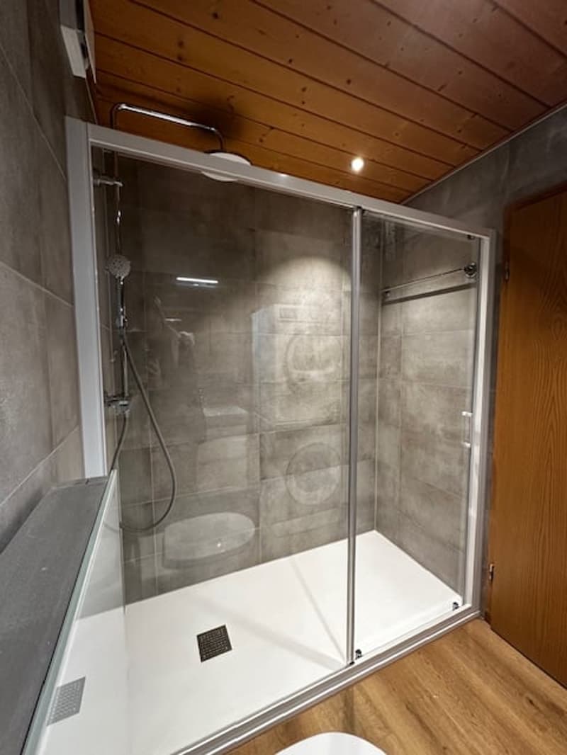 shower, gray tiles, washing machine visible, wooden ceiling