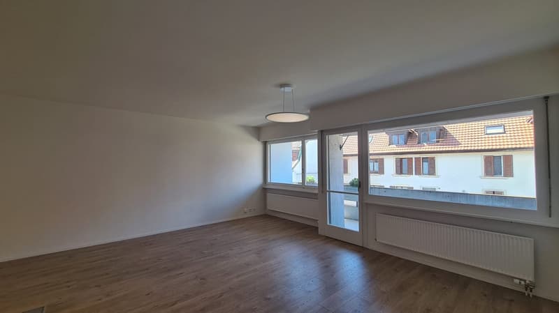 empty room, wooden floor, white walls, large windows, sliding door to balcony, ceiling lamp