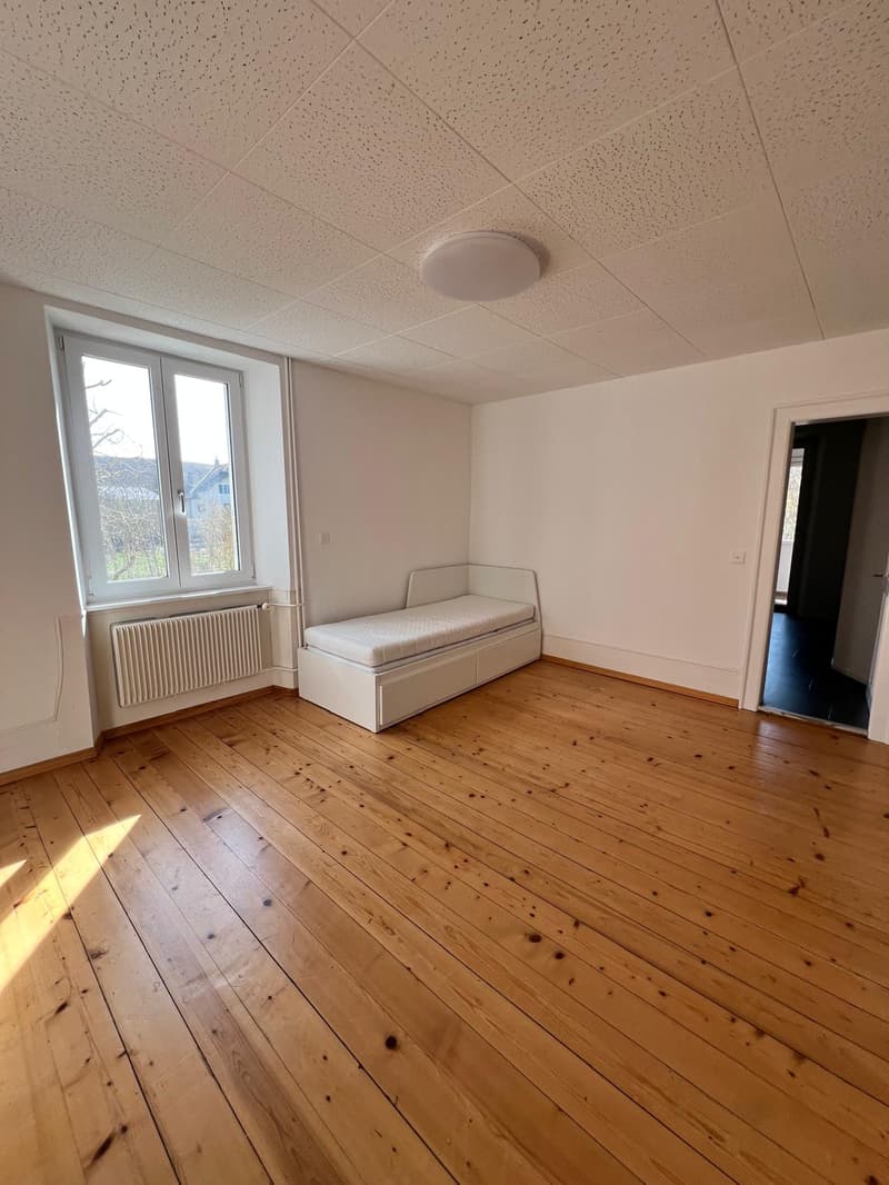 empty room, wooden floor, white walls, small bed, window with white frame, white radiator