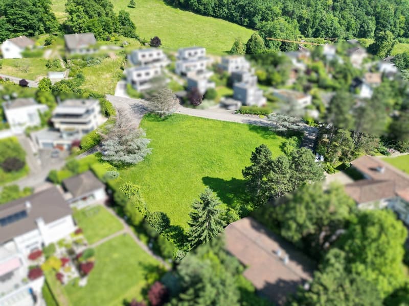 an aerial view of a building lot surrounded by houses and lush green trees and grass