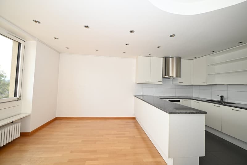 Empty kitchen with white cabinets, wooden floor, granite countertop, stainless steel range hood, white ceiling with recessed lighting, large window