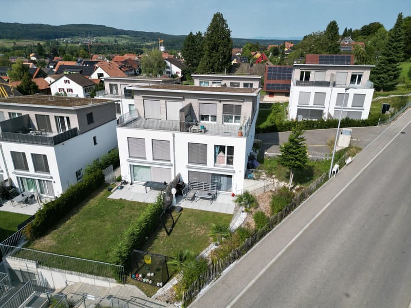 Modern apartment building with 4 units, solar panels, balconies, raised ground floor, garden, and parking