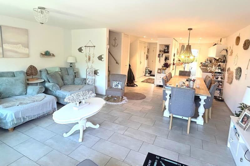 Open plan living and dining area with a view, modern decor, large windows, chandelier, dining table, chairs, couch, side table, rug, and decorative items