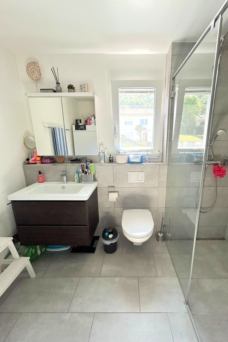 Bathroom with shower, sink, toilet, and storage cabinet