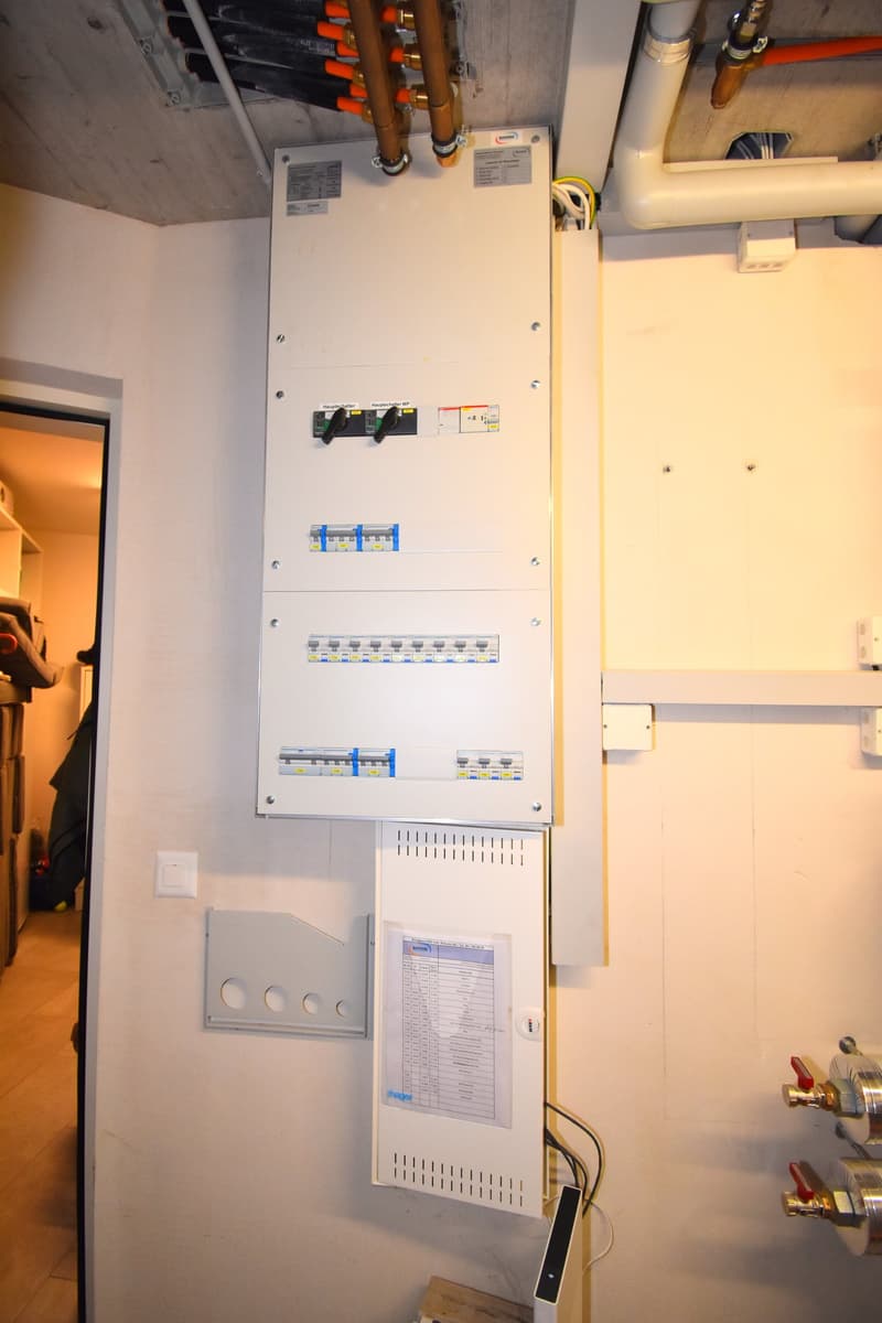 Electrical panel mounted on the wall, with multiple switches and a paper attached to it.