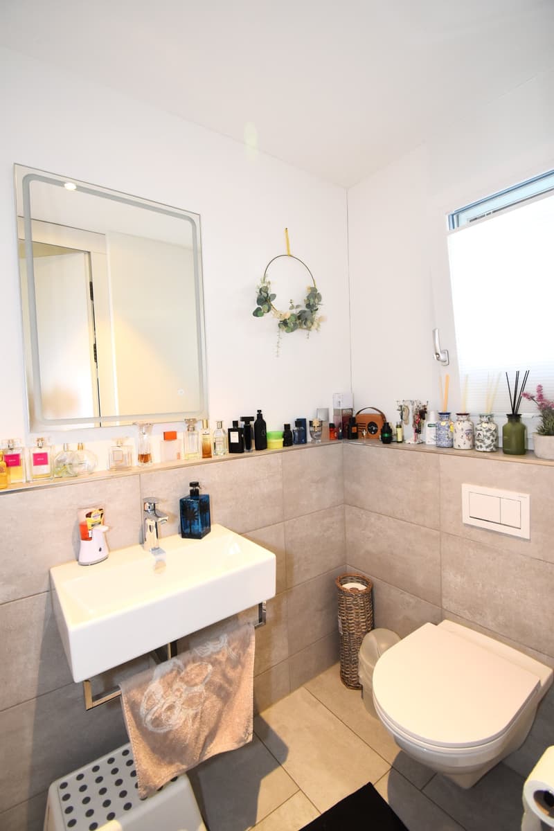 Bathroom with white sink, mirror, toilet, and tiled walls