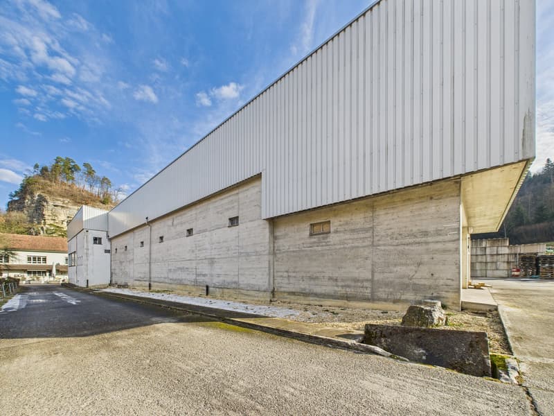 large concrete wall, white roof, concrete base, large driveway, white exterior