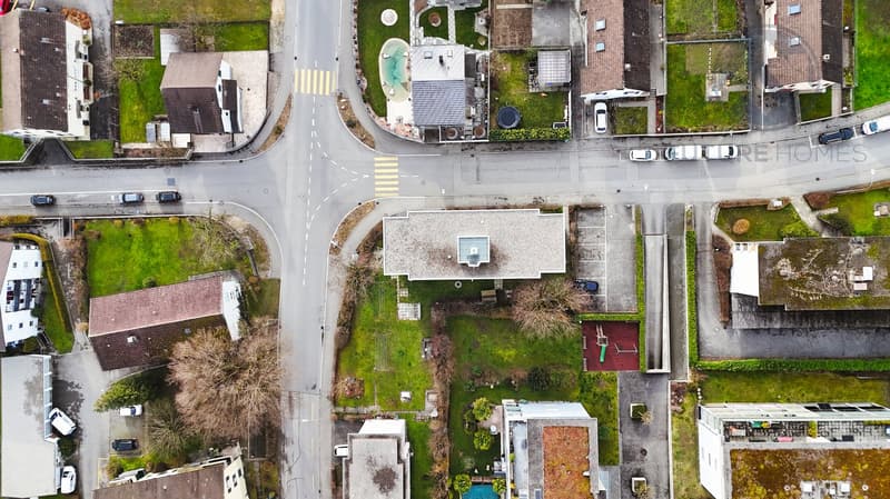 Aerial view of a neighborhood with several houses, a swimming pool, and a road intersection.