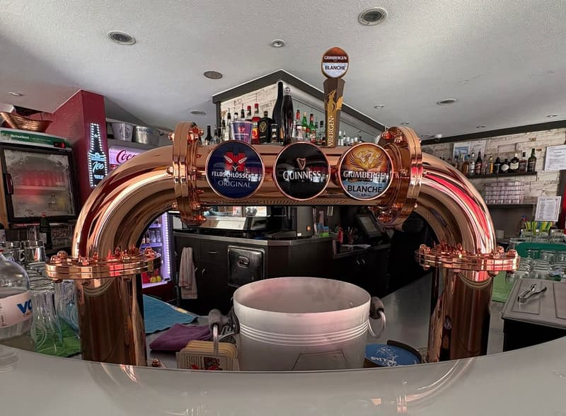 copper bar tap, bottles on display, glasses, counter with white bucket