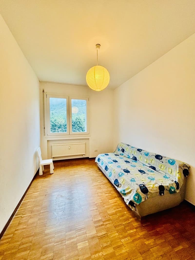 White walls, wooden floor, single bed, windows, white chair, ceiling lamp