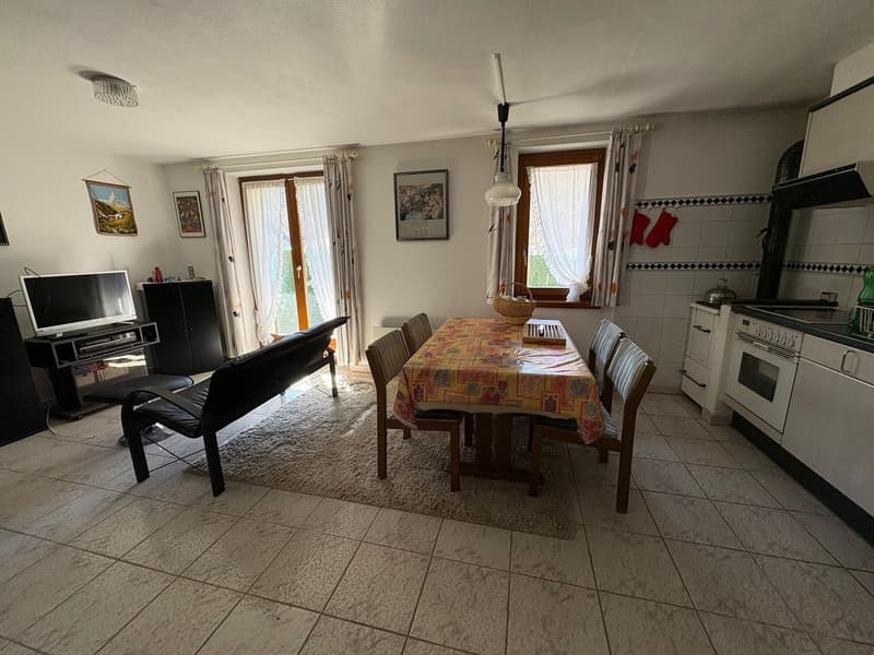 Dining room with a table, chairs, couch, TV, and a kitchen with a stove, oven, and cabinets
