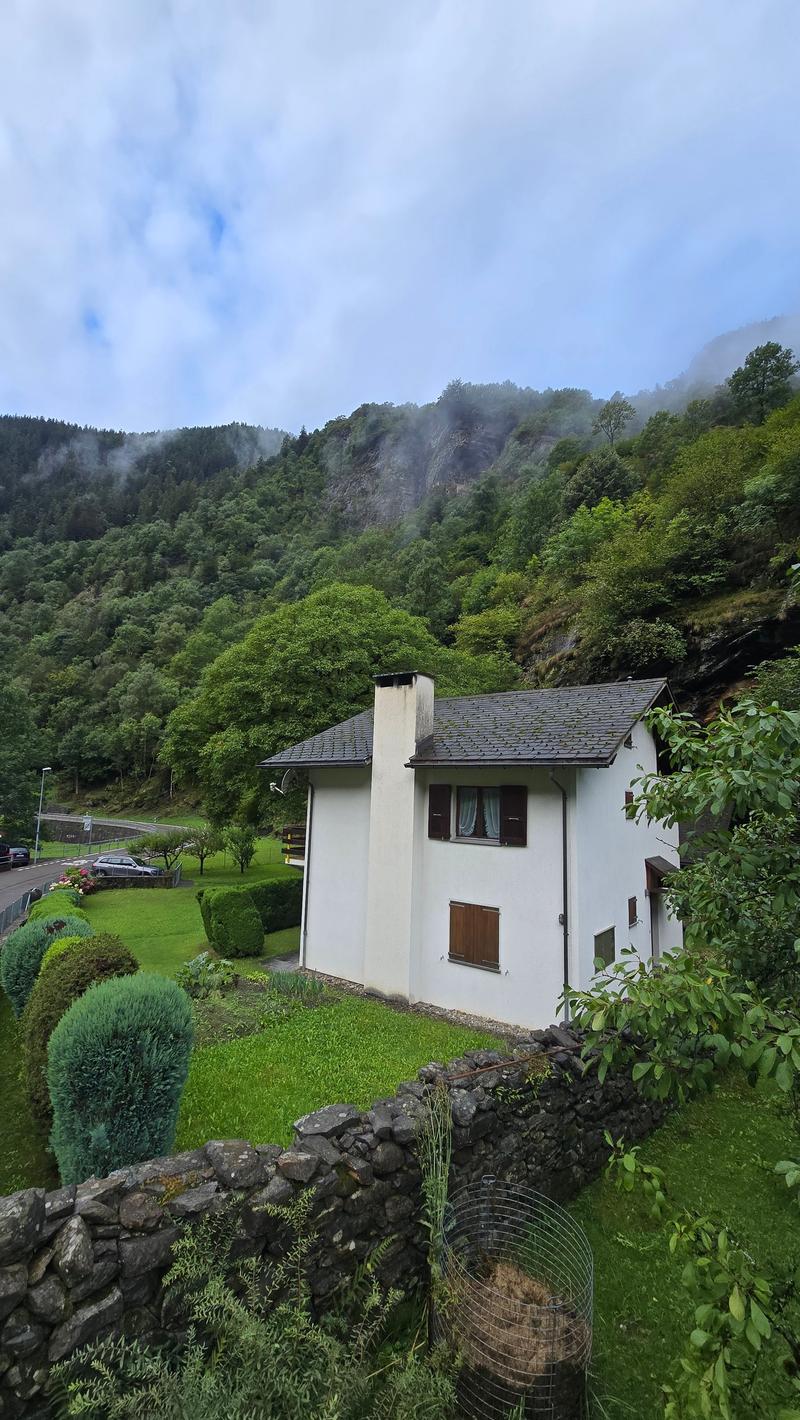 Detached white house on a slope, with a view to the mountains, large front garden, stone wall