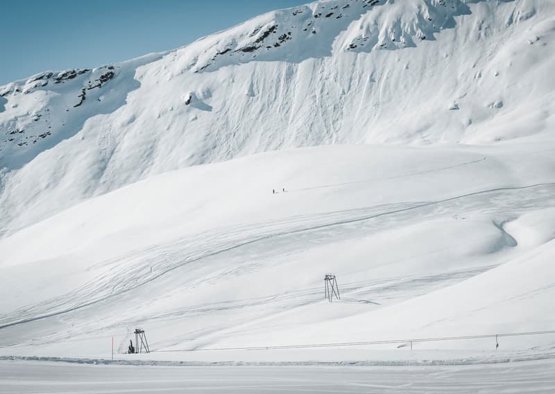 snowy mountain with skiers on the slope, poles in the snow