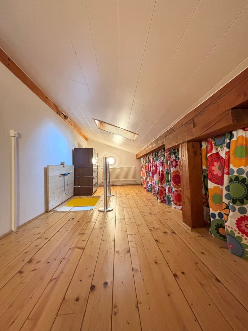 Wooden floor, white walls, exposed beams, large open space, wooden storage cabinet, radiator, yellow trapdoor