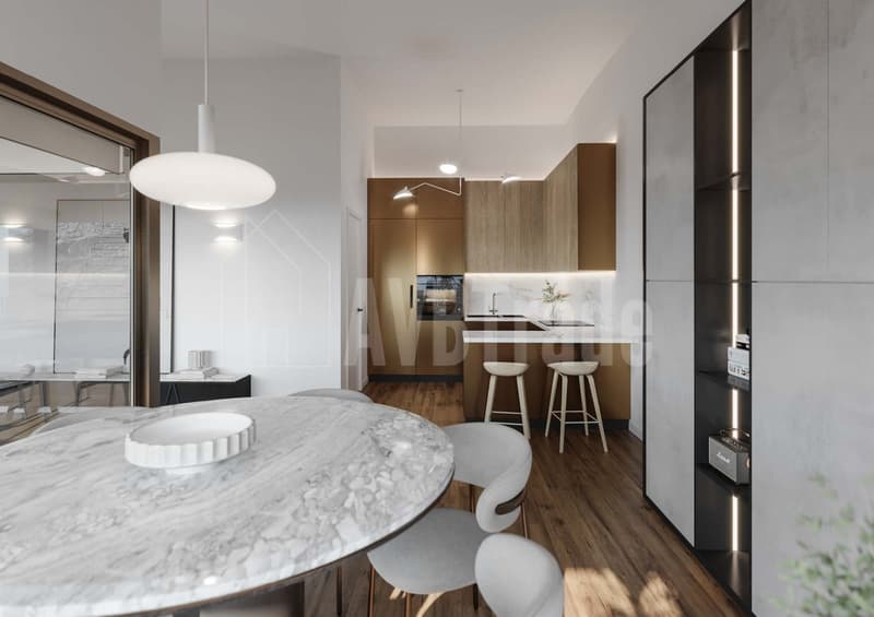 The image shows a modern and open-concept kitchen and dining area. The kitchen features wood-paneled cabinets, a marble countertop, and a built-in dishwasher. The dining area has a large round marble table with white chairs. The space is well-lit with pen