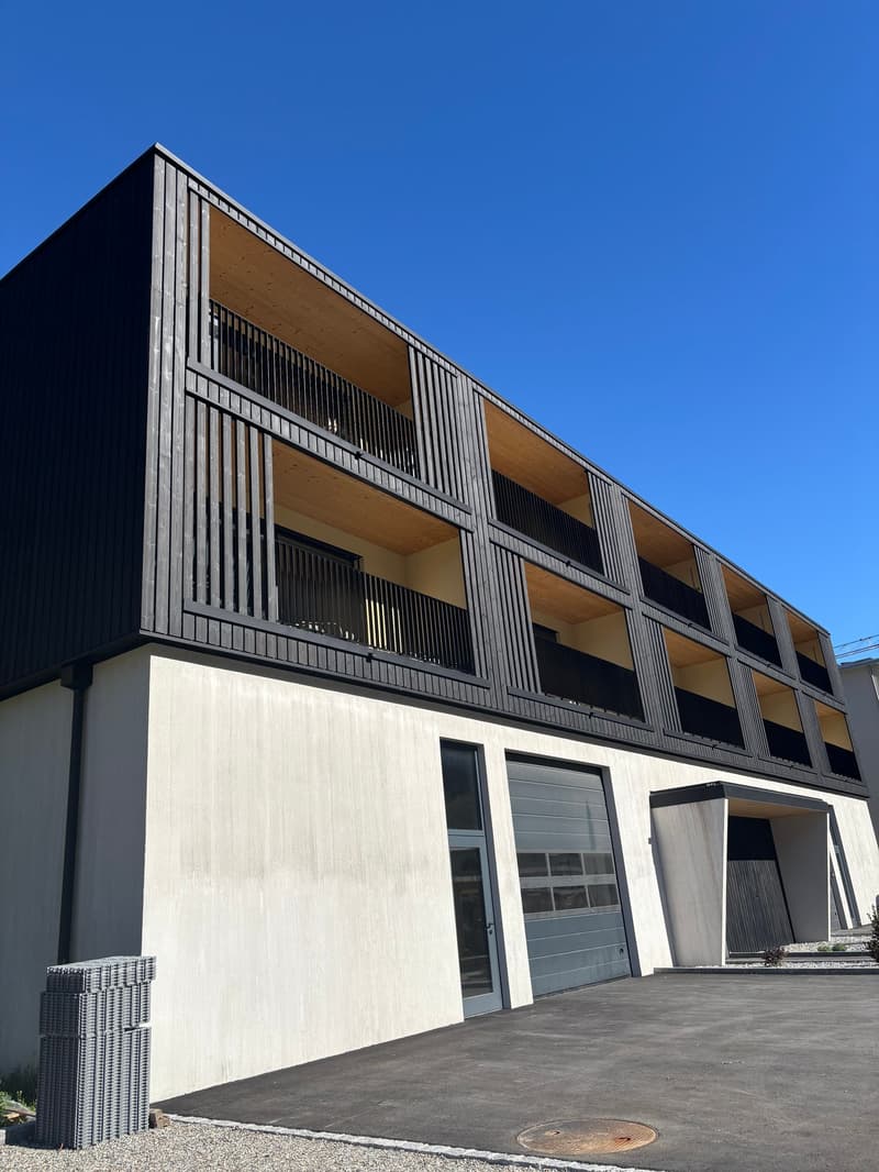 Modern house with black exterior, balconies, garage.