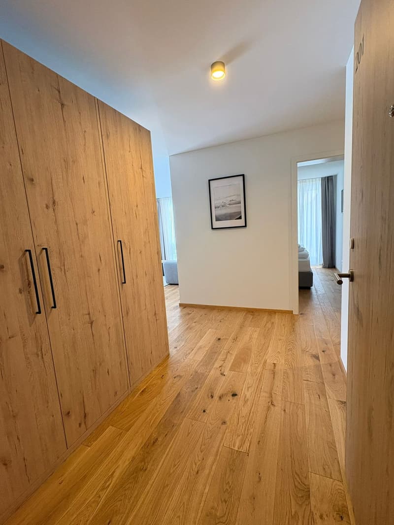 large wardrobe, white wall, picture frame, hardwood floor, open door, hallway